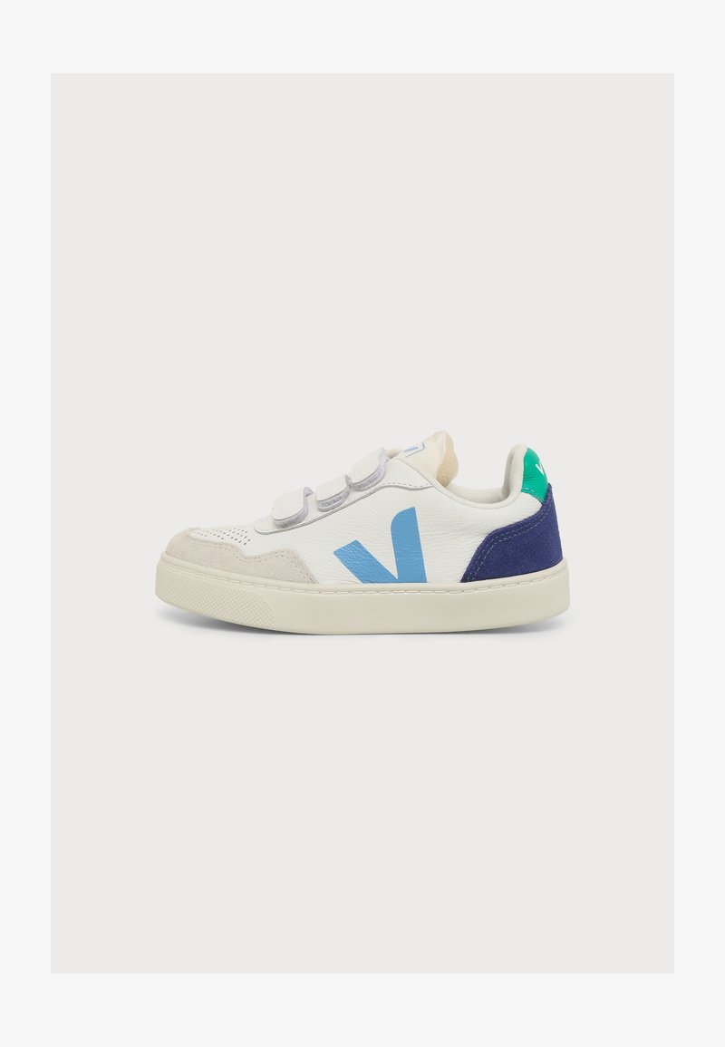Baskets basses blanches avec des accents bleus et verts, semelle beige et trois bandes Velcro grises.