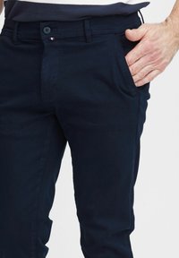 Mørkeblå bomuldsbukser med en glat tekstur, fem lommers design og en knaplukning med en lille tricolor detalje.