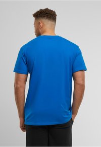 Blå bomulds T-shirt med korte ærmer, rund hals og en glat tekstur. Det bageste for view viser ingen grafik eller mønstre.