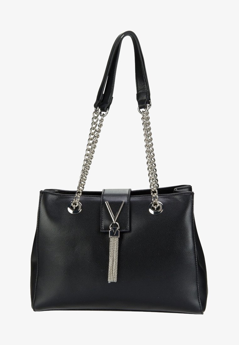 Bolso tote negro de cuero con un acabado texturizado, correas de cadena metálica, cierre magnético y un adorno de borla plateada.
