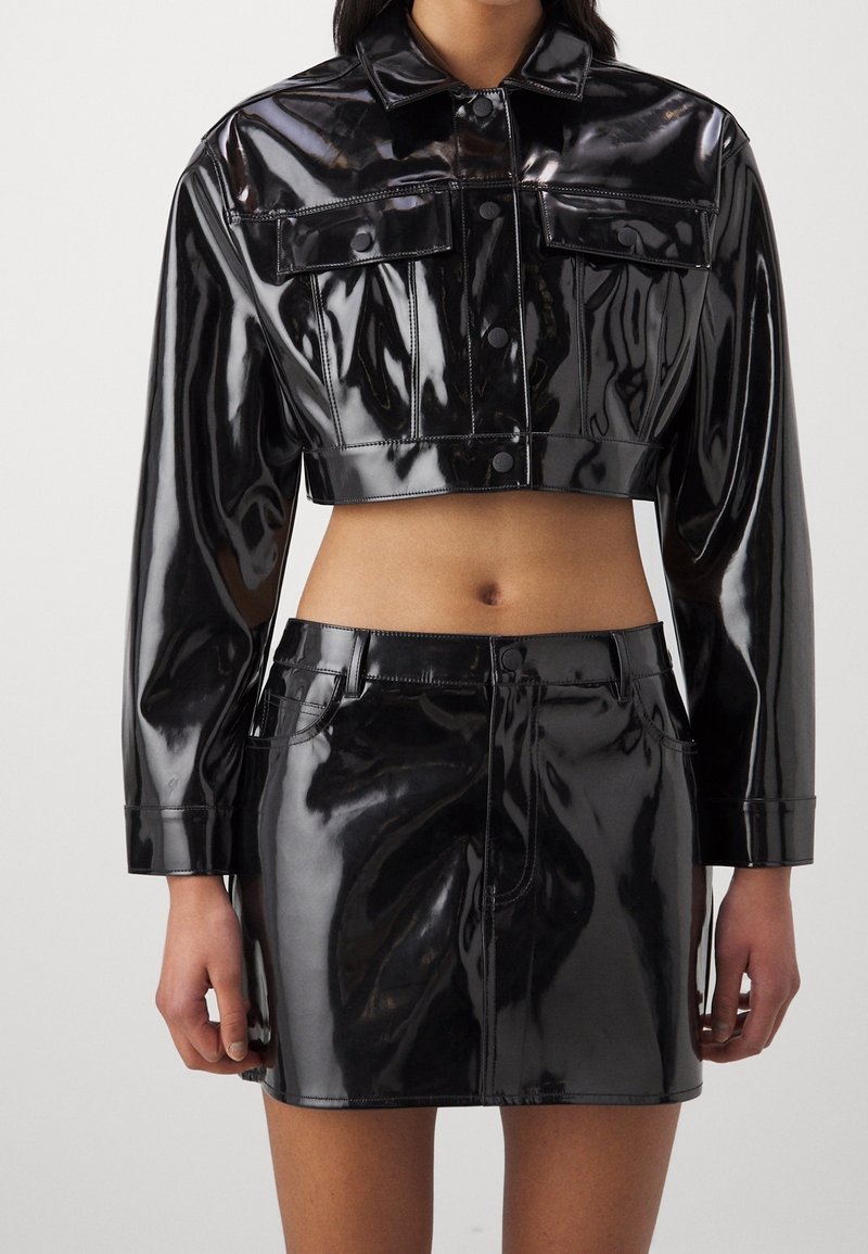 Black, glossy cropped jacket with two front pockets and button closure, paired with a matching black, high-waisted skirt. Smooth texture.