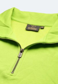 Grüner Reißverschluss-Pullover mit weicher Textur, hohem Kragen und gebrandetem Reißverschluss. Verfügt über ein Etikett mit "Switcher" und Pflegehinweisen.