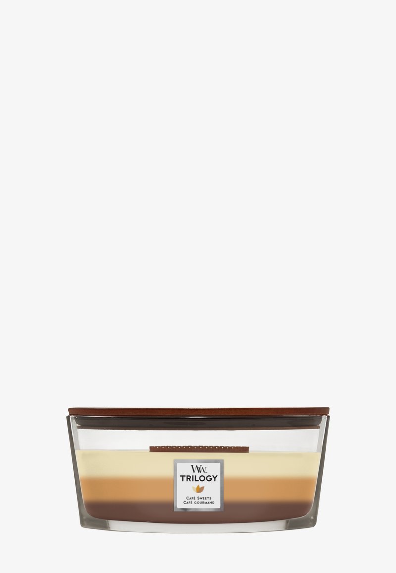 Bougie en verre avec trois couches de nuances crème, caramel et marron, étiquetée "Trilogy Café Sweets" avec une mèche en bois et un couvercle sur le dessus.