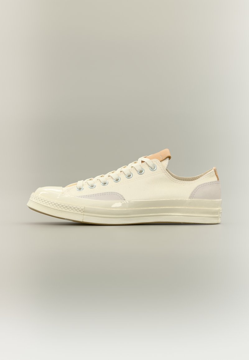 Καμβάς αθλη τικού παπουτσιού σε εκρού απόχρωση, με γυαλιστερό κάλυμμα στη μύτη και απαλές λεπτομέρειες. Επίπεδα κορδόνια και μεταλλικά πόρπες. Χαμηλό προφίλ σχεδίασης.