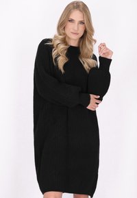 Zwarte gebreide trui-jurk met lange, volumineuze mouwen, geribbelde textuur en een relaxte fit, tot halverwege de dij.