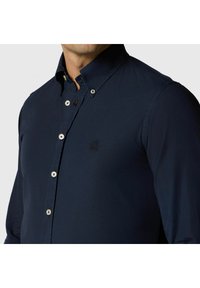 Camicia blu navy con bottoni, dal design aderente, con colletto aperto, bottoni a contrasto e logo ricamato sul petto.