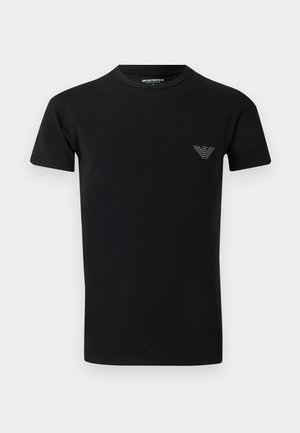Fekete rövid ujjú, kerek nyakú póló, kis Emporio Armani logóval a bal mellrészen, egyszínű háttér előtt.