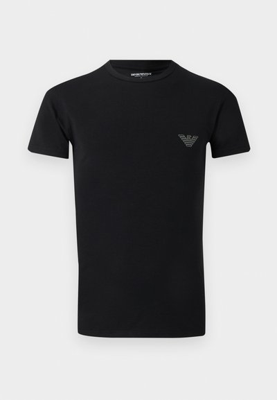 Μαύρο κοντομάνικο T-shirt με στρογγυλή λαιμόκοψη και μικρό λογότυπο Emporio Armani στο αριστερό στήθος, μπροστά σε μονόχρωμο φόντο.