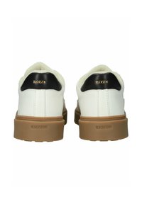 Biele kožené tenisky s hnedými gumovými podrážkami, čiernymi akcentmi na päte a mäkkým, krémovým podšívkou. Obsahujú embosované logo.