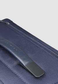 Dunkelblauer Stoffbeutel mit strukturierter Oberfläche, ausgestattet mit einem glatten Ledergriff und einem Metallreißverschluss. Keine sichtbaren Logos oder Muster.