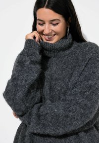 Grau oversized Rollkragenpullover mit einer weichen, flauschigen Textur und einem gerippten Kragen, der lange, lockere Ärmel und eine entspannte Passform aufweist.
