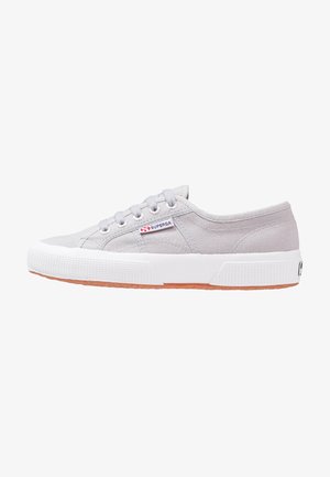 Baskets basses en toile gris clair avec semelle en caoutchouc blanche et lacets, avec un petit logo « Superga » sur le côté.