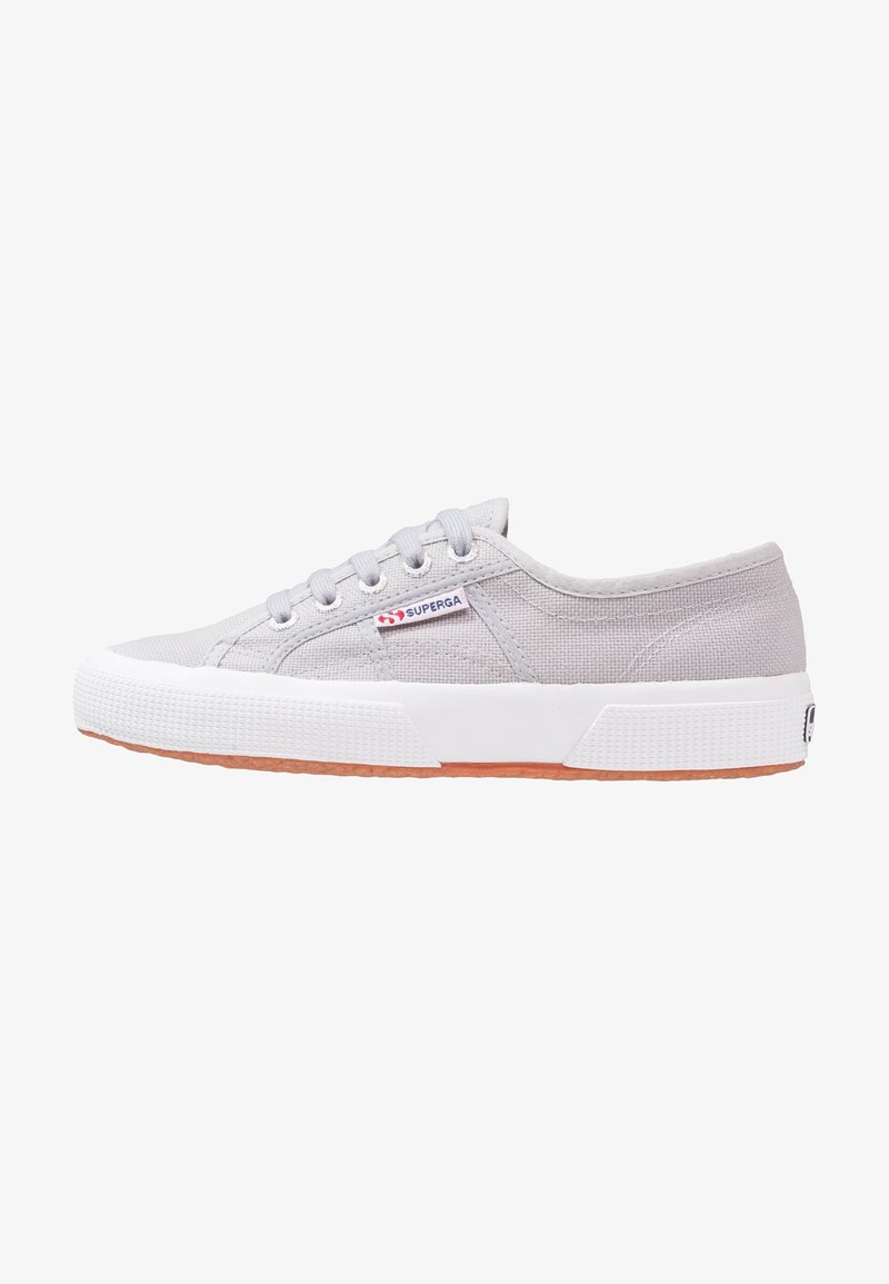 Baskets basses en toile gris clair avec semelle en caoutchouc blanche et lacets, avec un petit logo « Superga » sur le côté.