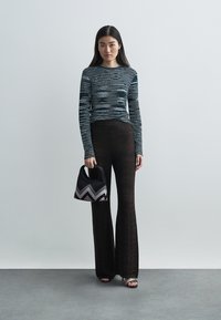 Ριγέ μακρυμάνικη μπλούζα, μαύρο παντελόνι με μοτίβο σε καμπάνα και μικρή μαύρη τσάντα με σχέδιο ζιγ-ζαγκ. Στρογγυλεμένα μαύρα και ασημένια στοιχεία σε σανδάλια.
