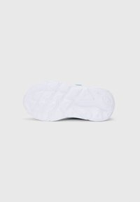 Hvit sneakersåle med teksturert gummimønster som har varierte mønstre. Jevn overflate, litt hevede detaljer nær hælen.