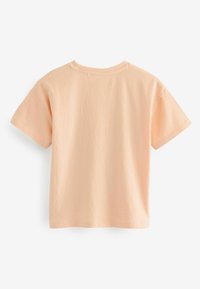 Persikofärgad bomull t-shirt med korta ärmar, rund halsringning och en mjuk textur. Rakt snitt utan synliga logotyper eller mönster.
