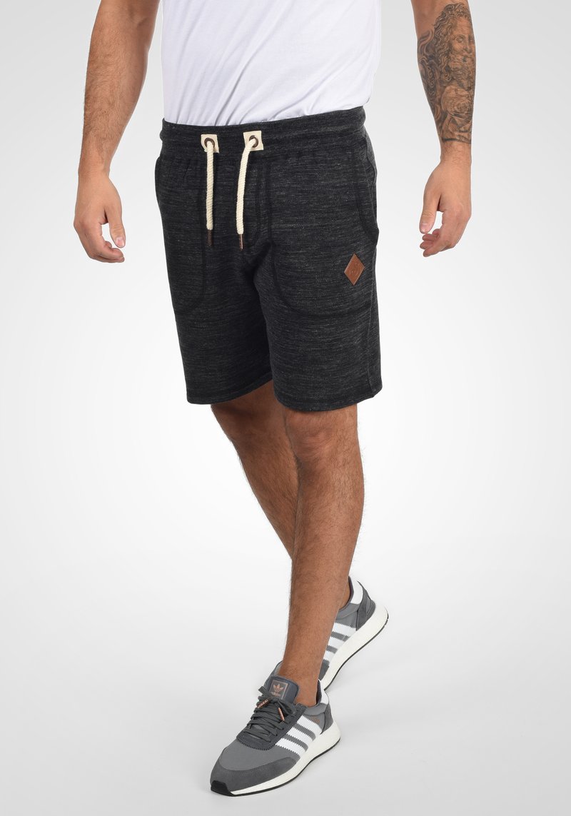 Mørkegrå træningsshorts med struktureret stof, elastisk talje, hvid snor, sidelommer og et lille diamantformet lædermærke.