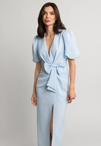 Niebieska sukienka z głębokim dekoltem w kształcie litery V, bufkowymi rękawami i paskiem w talii. Posiada rozcięcie po boku oraz gładką teksturę materiału.