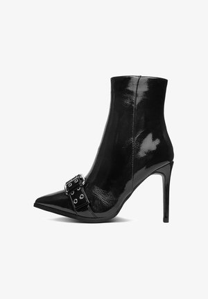 Mustmust musta nahknekk trelli, millel on terav nina, stilettokõrgus ja dekoratiivne pandla detail ninapool. Läikiv tekstuur.