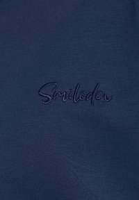 Tessuto blu navy con una superficie liscia caratterizzato dal logo ricamato "Smiledon" in filo scuro; design semplice senza ulteriori motivi.