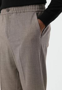 Grijze, gestructureerde broek met een relaxte pasvorm, voorzien van zijzakken, een knoopsluiting en een elastische tailleband.