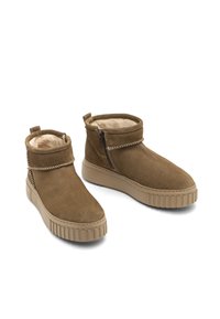 Botas de tobillo de ante marrón con forro de felpa, cierre de cremallera y suela de goma texturizada con estrías verticales. Diseño sencillo con puntera redonda.