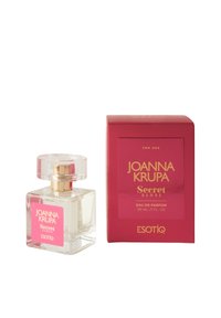 Przezroczysta szklana butelka perfum z różową etykietą i złotymi akcentami, obok żywej różowej pudełka z złotym tekstem i szczegółami zapachu.
