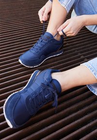 Marinefargede sneakers laget av skinn og semsket skinn, med snøring, teksturerte lapper og en hvit gummi såle.