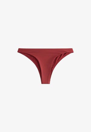 Femeie stând lângă piscină, purtând slip de bikini culoarea vișinie și sutien de bikini asortat, cu închizătoare metalică în spate.