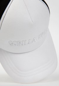 Witte pet met een zwarte accenten. Kenmerkt zich door geborduurde "GORILLA WEAR" tekst aan de voorkant, gemaakt van soepele stof met een gestructureerde vorm en stikdetails.