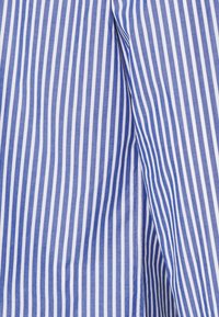 Tela de rayas verticales en azul y blanco con una textura suave y bordes definidos, que presenta un detalle de abertura en un lado.
