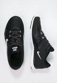 Mustat urheilukengät, jotka on valmistettu verkosta ja synteettisistä materiaaleista. Varustettu valkoisella Nike-logolla, tekstuuripinnalla ja erottuvilla nauhoilla.