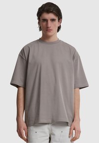Tricou din bumbac gri de mari dimensiuni, cu mâneci scurte, guler rotund, textură netedă și fără modele sau accente vizibile.