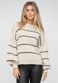 Sweter wyplatany w kolorze kremowym z czarnymi poziomymi paskami. Posiada luźny krój, okrągły dekolt i ściągacze. Teksturowany materiał.