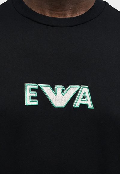Μαύρο μπλουζάκι με εξέχον κεντητό λογότυπο «EWA» σε λευκό με πράσινες λεπτομέρειες. Ομαλή υφή και σχέδιο με στρογγυλή λαιμόκοψη.