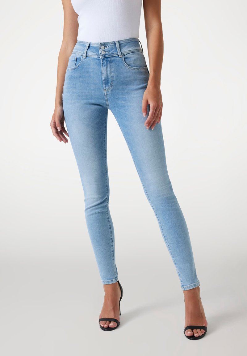 Jean taille haute bleu clair en denim extensible avec une coupe ajustée, des coutures minimales et un style à cinq poches.