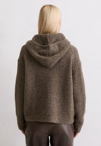 Brązowy, teksturowany hoodie z szerokim dekoltem i ściąganym kapturem. Charakteryzuje się luźnym krojem i ribbowanym dołem, wykonany z miękkiego, ciepłego materiału.