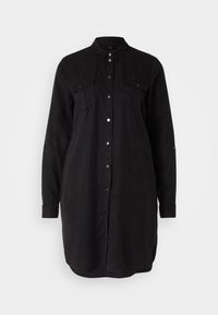Abito camicia lungo nero con maniche lunghe e due tasche sul petto con bottone, esposto su uno sfondo bianco semplice.