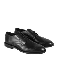 Des chaussures habillées en cuir noir présentent une surface lisse, des détails en brogue, un bout pointu et un petit talon empilé. Les lacets sont positionnés au centre.