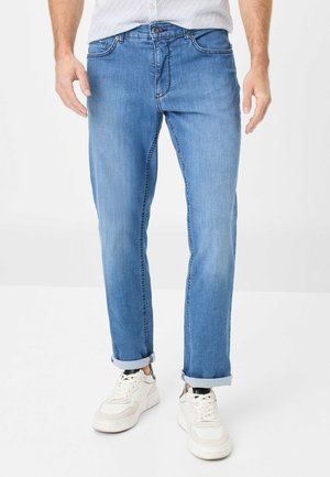 Lichtblauwe denim jeans met een rechte snit, opgerolde pijpen, standaard zakken en subtiele vervaging, gedragen met witte sneakers.