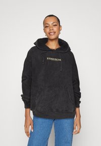 Schwarzer, oversized Hoodie mit einer vorderen Tasche, Kapuze mit Zugband und dem Text "ZODIACUS" in Gold auf der Brust. Weicher Stoff und lässige Passform.