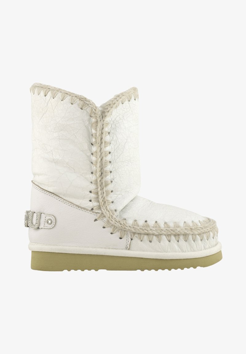 Stivale in pelle bianca con finitura texturizzata, cuciture decorative e suola chiara a contrasto. Presenta un dettaglio con fibbia argentata.
