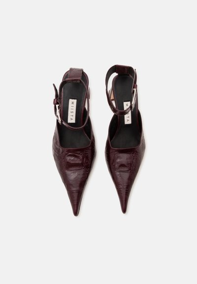 Ζευγάρι σκουρόχρωμα βουργουνδί slingback παπούτσια με μυτερή μύτη, υφή και λουράκια στον αστράγαλο, με την ένδειξη "MIISTA" στο εσωτερικό.