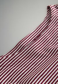 Triibuline puuvillane kangas sügavpunastes ja valgetes toonides, millel on pehme tekstuur. Disainis on horisontaalsed triibud ja ümardatud kaelus.