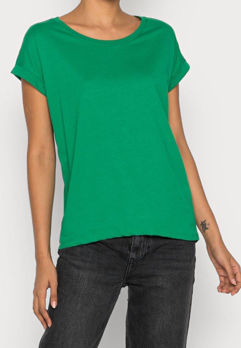 Grön kortärmad T-shirt i mjuk bomull, med rund halsringning och uppvikta ärmar, i kombination med mörka jeans. Enkelt design, enfärgad.