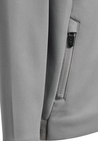 Hellgraue Jacke aus strukturiertem Stoff, mit einer Reißverschlusstasche und verstärkten Nähten. Glatte Oberfläche mit minimalistischen Designelementen.
