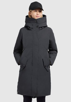 Black long coat with a high collar, side pockets, and a button closure. Made of smooth, water-resistant fabric. Accompanied by a black cap.