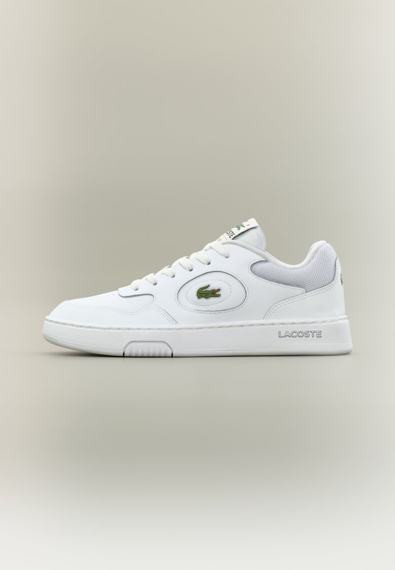 Weiße Leder Sneaker mit Mesh-Akzenten, runder Zehenpartie und flachen Schnürsenkeln. Mit grünem Krokodil-Logo und "LACOSTE"-Branding an der Ferse.