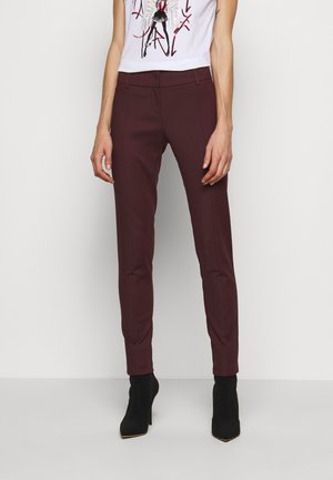 Wąskie, ciemnofioletowe spodnie do kostek noszone z czarnymi, spiczastymi botkami na wysokim obcasie oraz białym, graficznym krótkim topem.