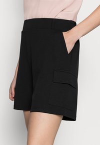 Sorte strækshorts med en glat overflade, der har en sidelomme og en afslappet pasform, designet til komfort og alsidighed.